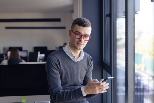 Young entrepreneur in his office taking a break, texting